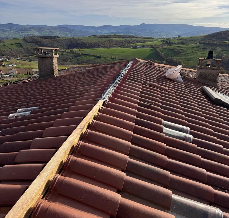 Faîtage en cours de réfection sur une toiture en tuiles dominant les coteaux